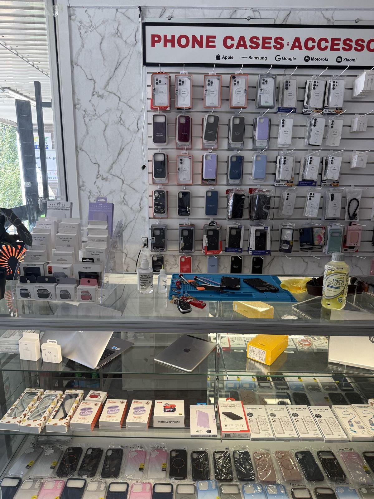 Wall of phone cases and accessories inside Davie Mobile, with the repair counter in front